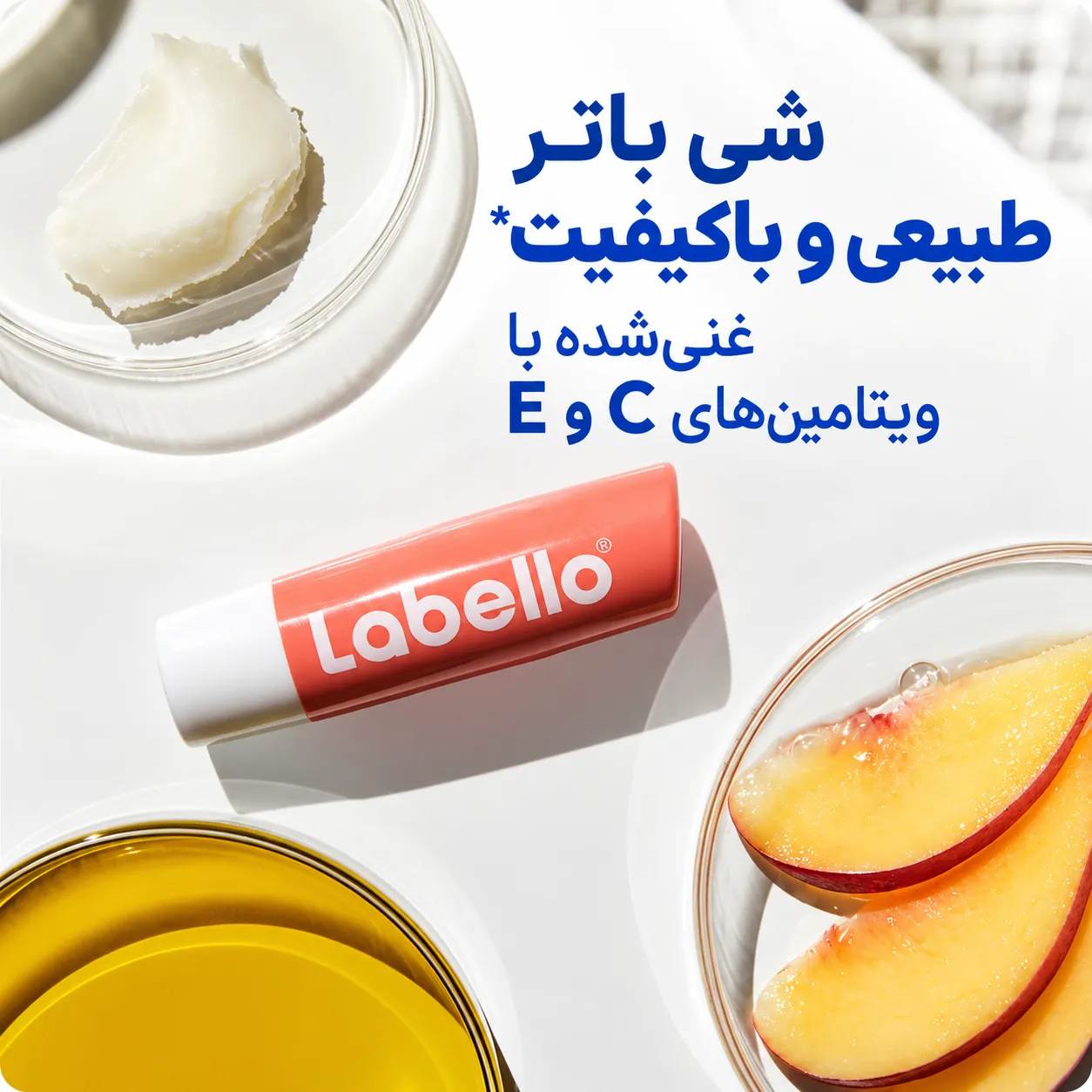 بالم لب هلویی لبلو در بسته‌بندی سفید و مرجانی، کنار برش‌های هلو و کاسه‌های مواد طبیعی